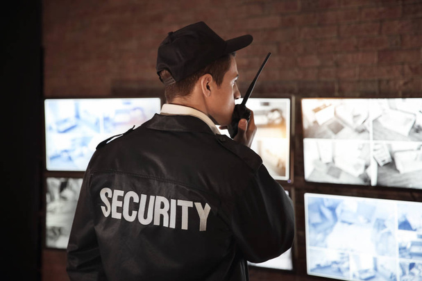 Male security guard using radio transmitter in surveillance room - 写真・画像