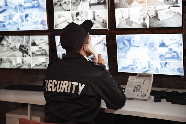 Mannelijke bewaker praten via de telefoon in de kamer van toezicht - Foto, afbeelding