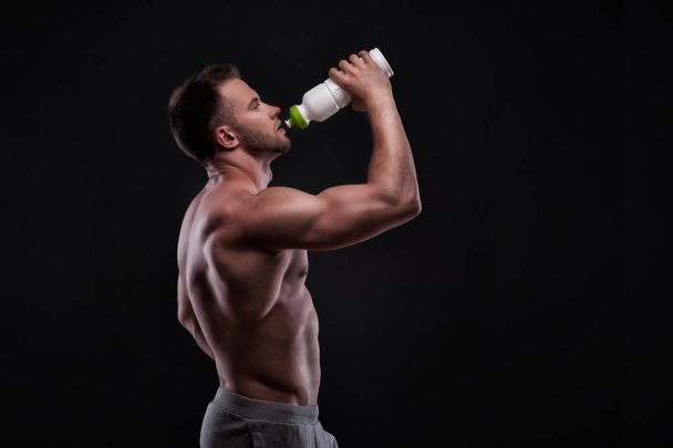 Muscular guy drinking water after training - 写真・画像