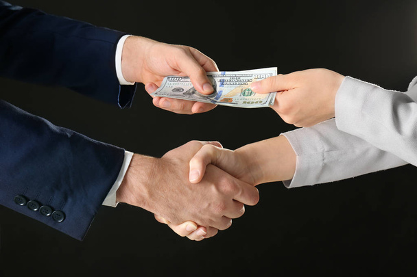 Businessman taking bribe from woman on black background - Фото, изображение