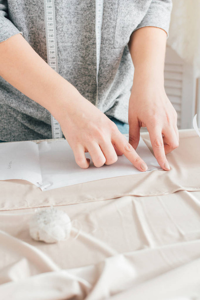 Young seamstress makes clothes cutting fabric - Fotó, kép