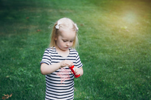 Little girl inflate soap bubbles on the lawn - Foto, Imagem