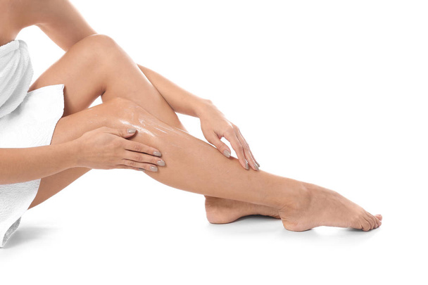 Mujer aplicando crema corporal en su pierna sobre fondo blanco, primer plano
 - Foto, imagen