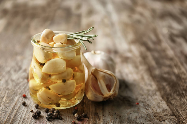 Preserved garlic in glass jar on table - Fotó, kép