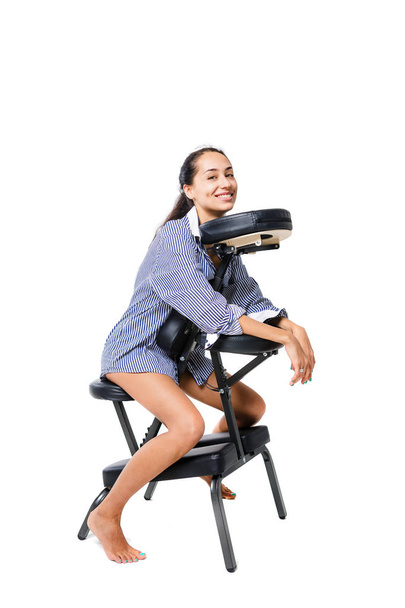 美しい若い女の子ブルネット オフィス ワーカー シャツとマッサージの椅子に座っている裸の脚。褐色肌とブルネットの髪。ビジネス コンセプトとマッサージ - 写真・画像
