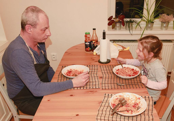 Dochter en vader in de keuken spaghetti eten voor het diner. - Foto, afbeelding