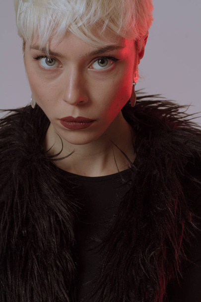 Hermosa chica rubia con pelo corto y maquillaje en un abrigo de piel negro
 - Foto, imagen