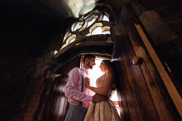 The boy gently embraces his beautiful girl near the wooden door  - Photo, Image
