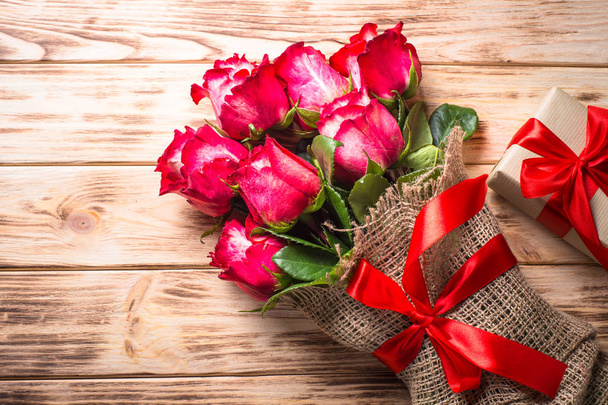 Κόκκινο τριαντάφυλλο λουλούδι και παρόν πλαίσιο στο ξύλινο τραπέζι. - Φωτογραφία, εικόνα