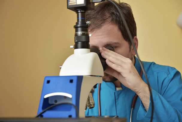 Young doctor researching on a microscope - 写真・画像
