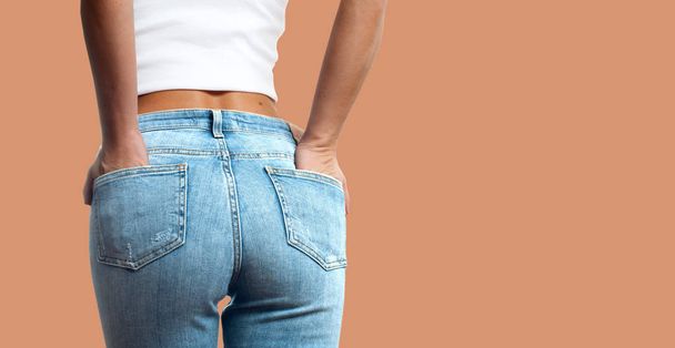 Female bottom in tight jeans on pastel background - Φωτογραφία, εικόνα
