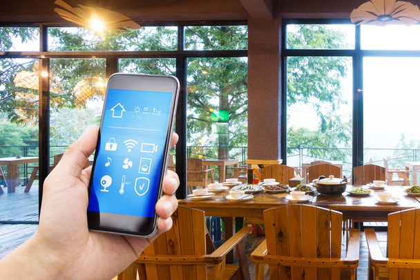 Smartphone met slimme huis en moderne restaurant in hotel - Foto, afbeelding
