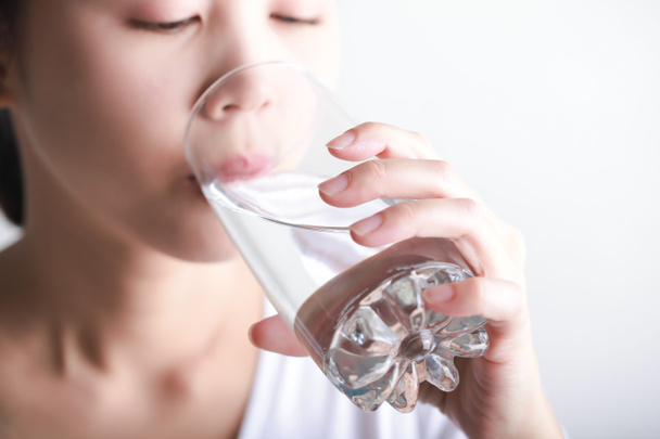 Молода жінка п'є чисту воду в руці
. - Фото, зображення