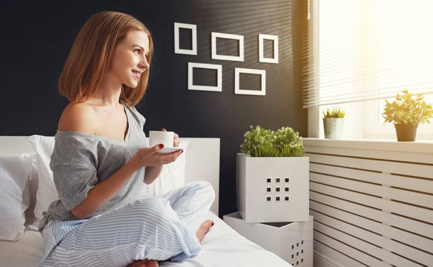 onnellinen nuori nainen kupin aamulla kahvia sängyssä
 - Valokuva, kuva
