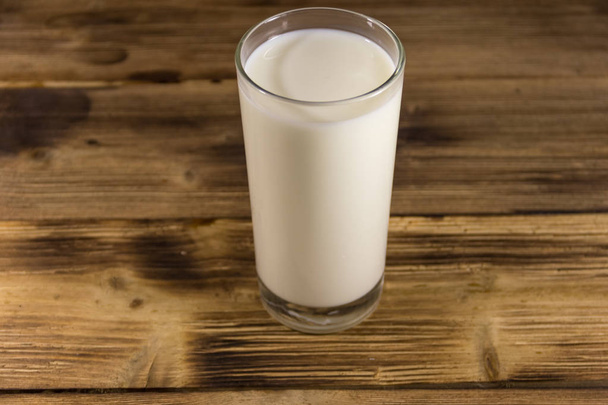Glass of milk on wooden table - 写真・画像