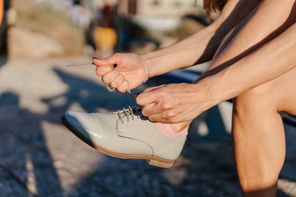 Молода жінка зв'язує взуття в парку
 - Фото, зображення