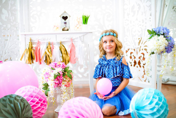 A portrait of a beautiful little girl laughs in a studio decorated many color balloons - Фото, зображення