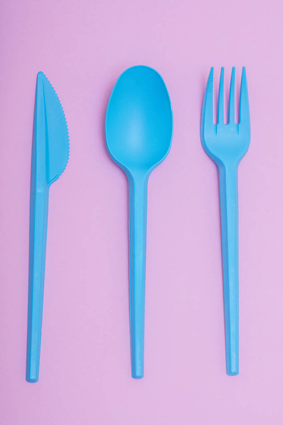 blue plastic cutlery set on pink background. - Photo, Image