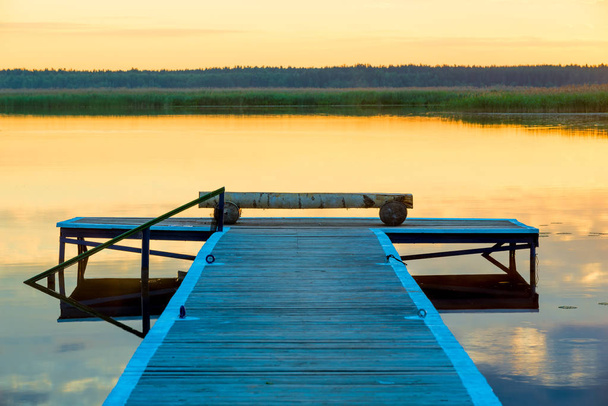 vista de un muelle de madera cerca de un pintoresco lago tranquilo al amanecer
 - Foto, imagen