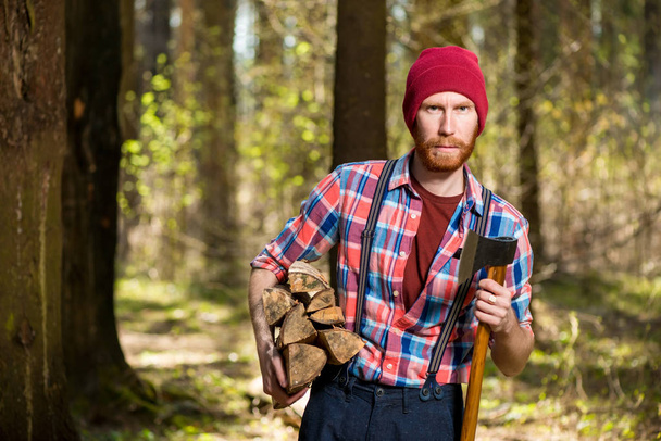 a forester with a beard carries wood and an ax, shooting in the  - Photo, Image