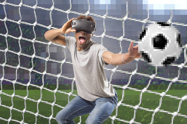 black afro American man using vr virtual reality 3D goggles playing soccer football video game with pixelated computer goal and stadium  - Photo, Image