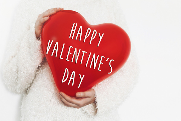 happy valentine's day text on red heart balloon in female hands  - Fotografie, Obrázek