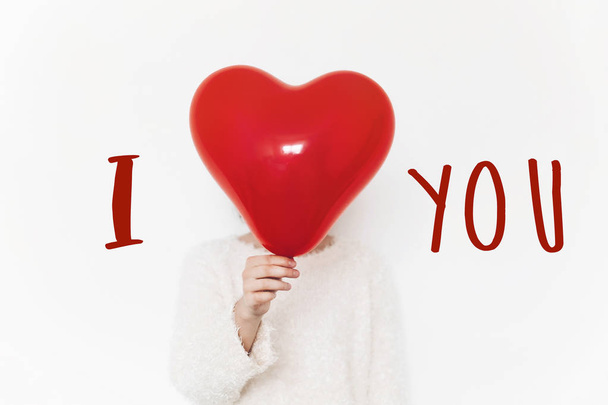 i love you text sign on heart. happy valentine's day concept. hand holding red heart balloon on white background with space for text. greeting card - Foto, afbeelding