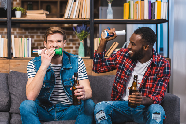 happy young multiethnic friends drinking beer and watching tv - Fotó, kép