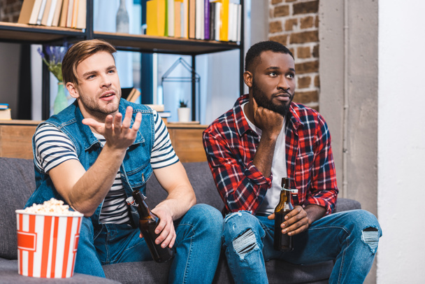 young multiethnic men drinking beer and watching tv together - Fotó, kép