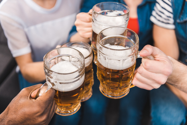 primer plano vista parcial de jóvenes amigos sosteniendo vasos de cerveza en las manos
 - Foto, imagen