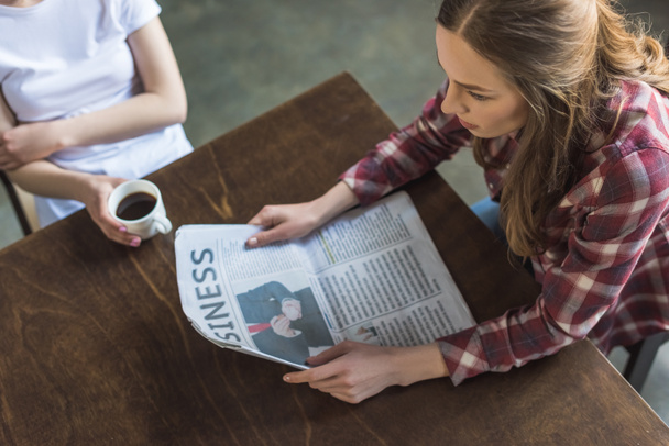 korkea kulma näkymä naisten lukeminen sanomalehti ja kahvin juominen keittiössä
 - Valokuva, kuva