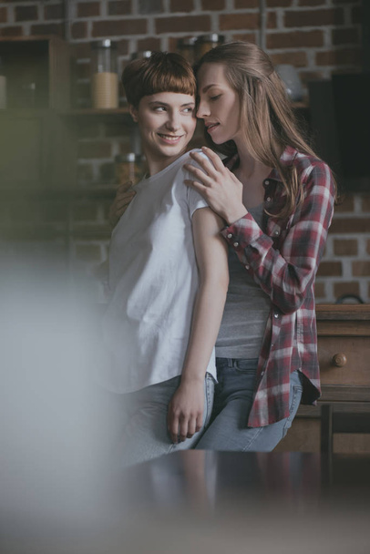 evde mutfak üzerinde gülümseyen genç lezbiyen çift - Fotoğraf, Görsel