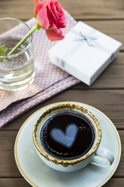 Sydän heijastuu kupin kahvia pöydälle ruusun vieressä. Ystävänpäivä käsite
 - Valokuva, kuva