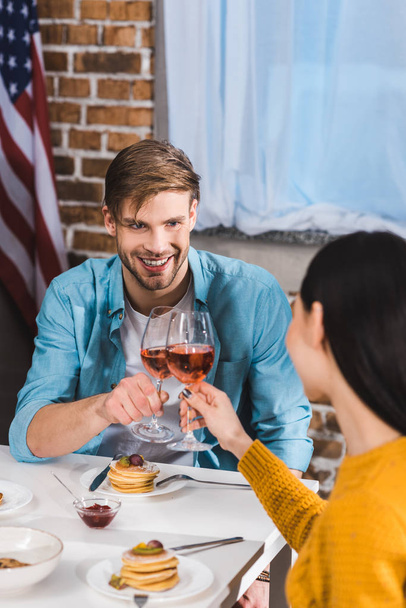 happy young couple clinking wine glasses while eating together at home - Photo, Image