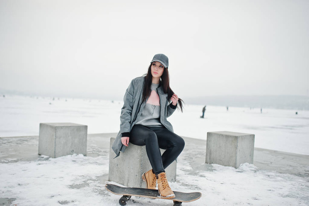 Stylish brunette girl in gray cap, casual street style with skat - Фото, изображение