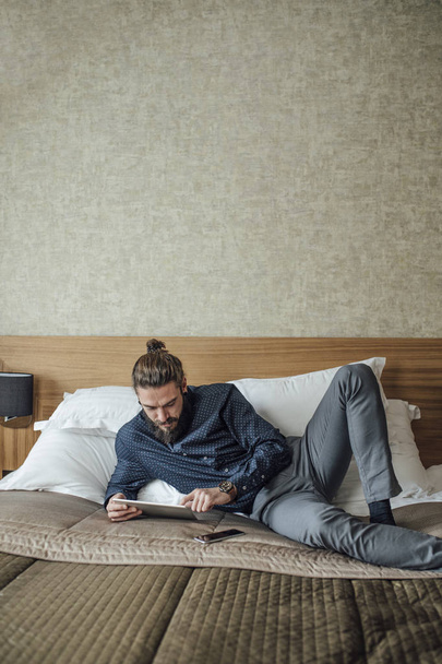 Man Lying on Bed and Reading on Tablet - Foto, imagen