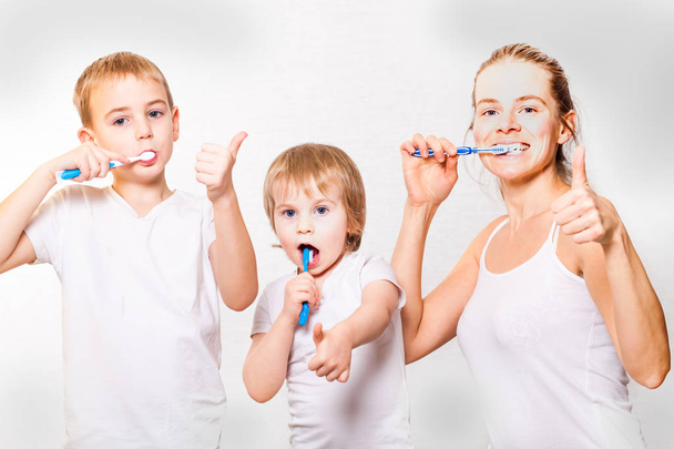 family mom and two blond boys brush their teeth - Fotoğraf, Görsel