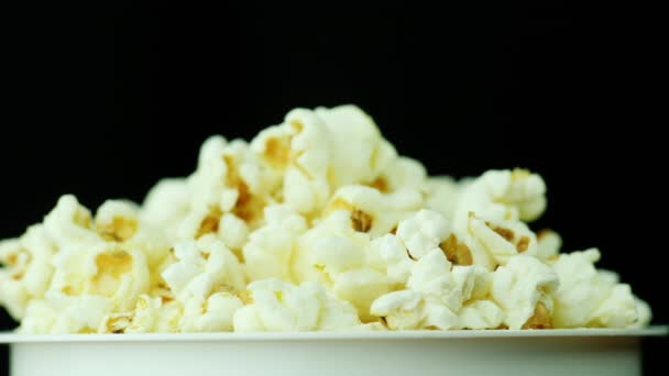 A glass of popcorn on a black background. Slowly rotates - Footage, Video