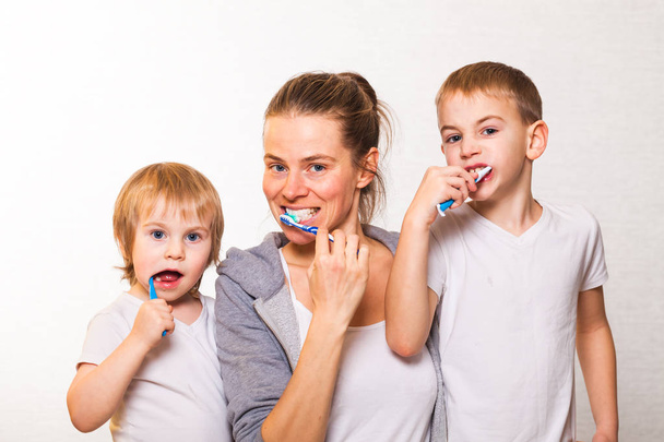 family mom and two blond boys brush their teeth - Photo, Image