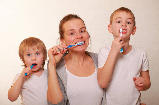 Familienmutter und zwei blonde Jungen putzen sich die Zähne - Foto, Bild