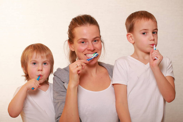 家族のママと二人の金髪の少年が歯を磨く - 写真・画像