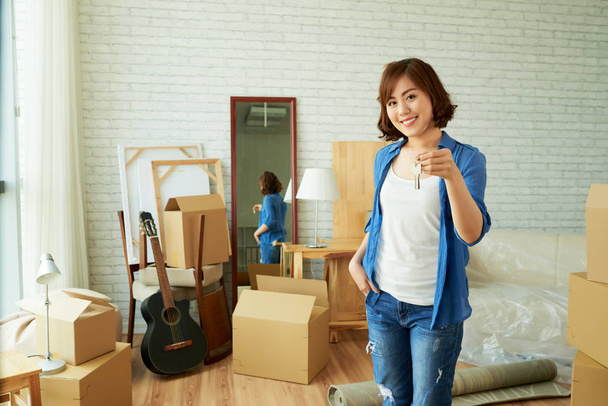 hermosa mujer asiática joven en la habitación con cajas de cartón con llaves de la puerta
 - Foto, imagen