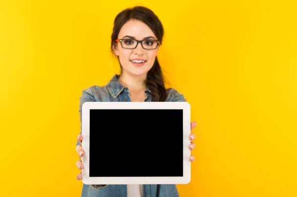 Μελαχρινή νεαρή γυναίκα δείχνει ψηφιακή δισκίο με την κενή οθόνη - Φωτογραφία, εικόνα