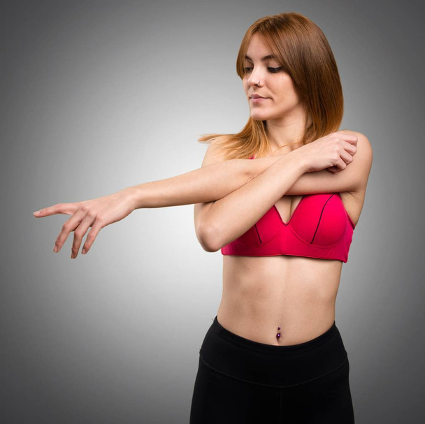 Sport nő, nyúlik a szürke háttér - Fotó, kép