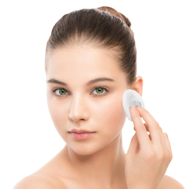 Young woman cares for face skin. Cleaning perfect fresh skin using cotton pad. Isolated. - Photo, image