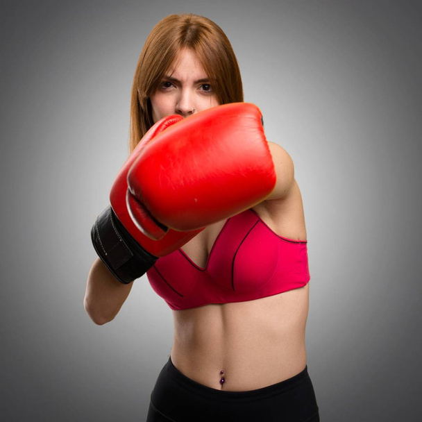 Jeune femme sportive avec gants de boxe sur fond gris
 - Photo, image