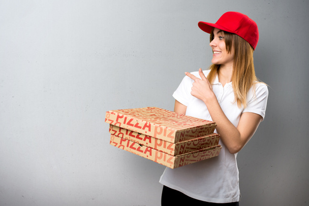Доставка пиццы женщина указывая на текстурированный фон
 - Фото, изображение