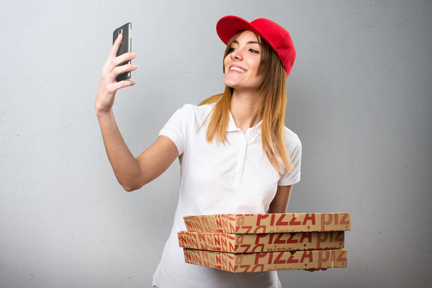 Pizza entrega mulher fazendo uma selfie no fundo texturizado
 - Foto, Imagem