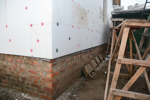Renovação da parede da casa com isolamento rígido externo da placa de isopor ao ar livre para economia de energia
. - Foto, Imagem