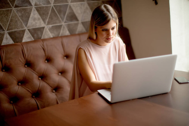 Mooie jonge vrouw die werkt op laptop in het café - Foto, afbeelding